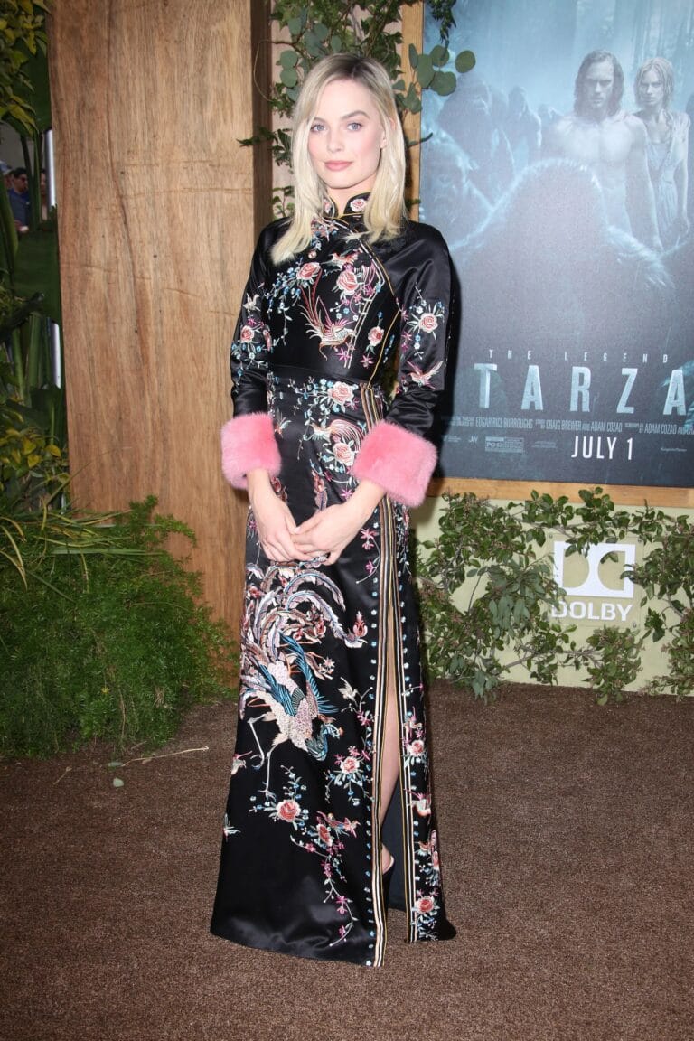 Margot Robbie: Wears a long black silk dress with floral embroidery and pink details…