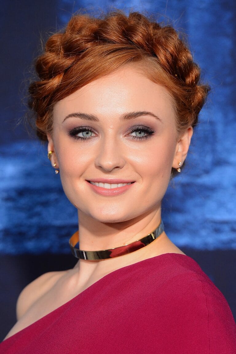 Sophie Turner: Luce un vestido de un solo hombro en tonos burdeos que resalta su elegante…