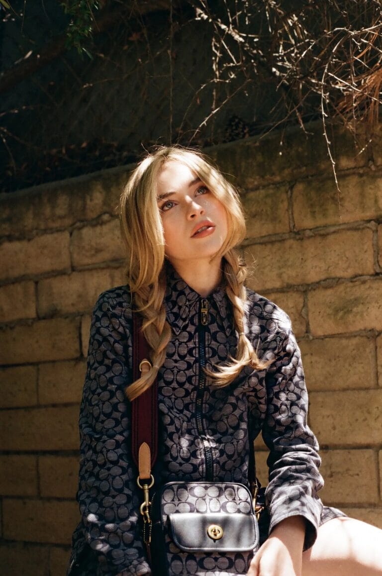 Sabrina Carpenter: Luce una chaqueta con un patrón geométrico en tonos oscuros, sentada sobre una superficie…