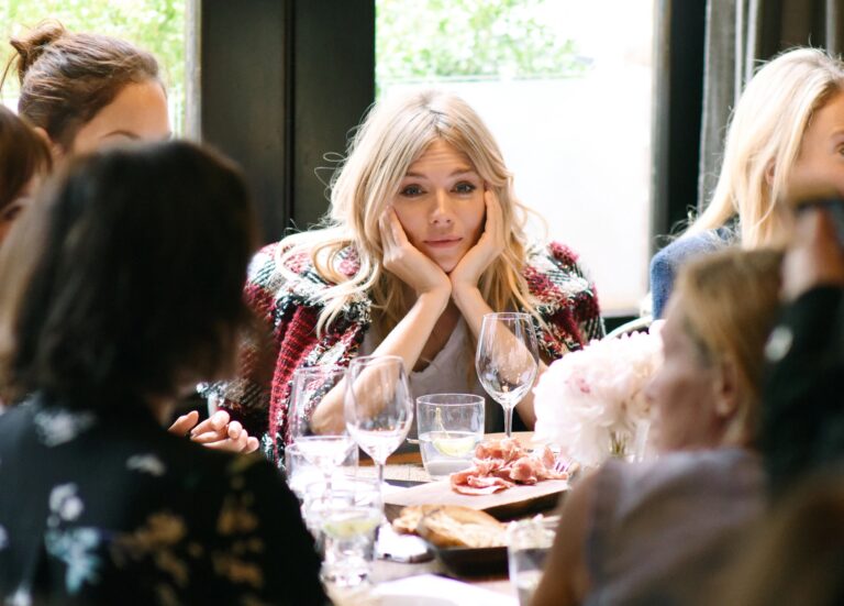 Sienna Miller: Wears a knit sweater over a white blouse, with a thoughtful pose while…