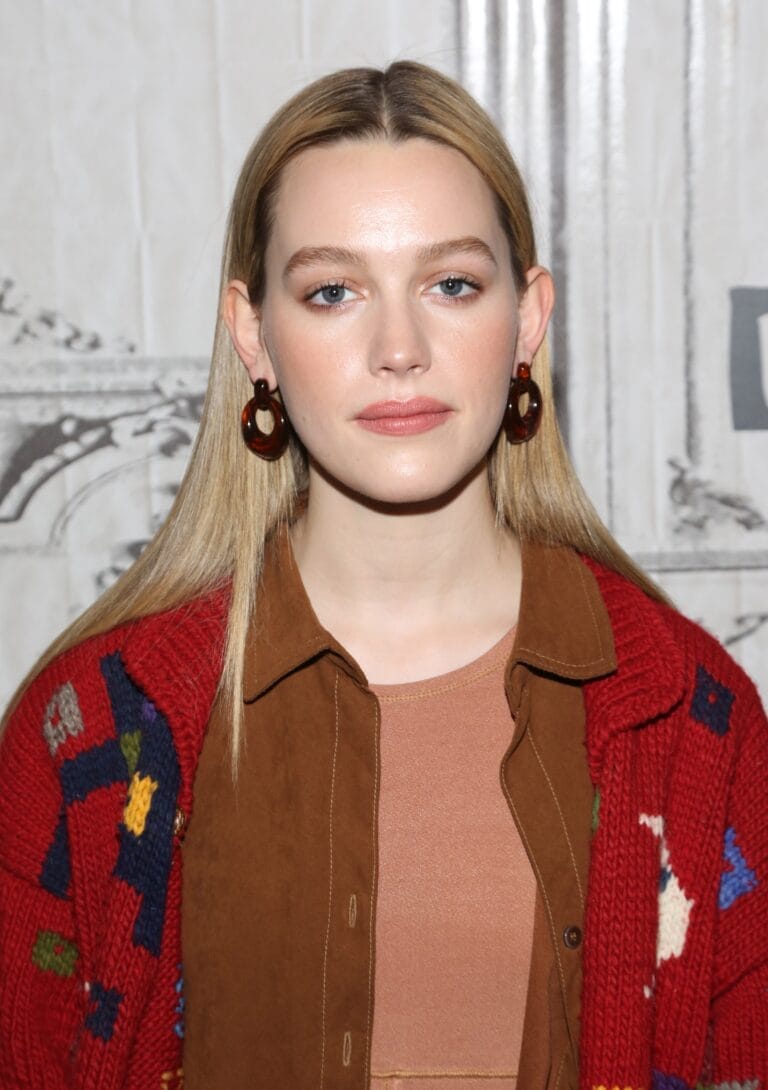 Victoria Pedretti: Wears a warm layered look, with a red knit sweater and colorful…