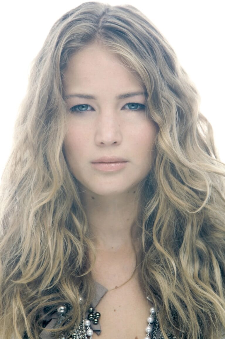 Jennifer Lawrence: Wearing a top adorned with chains and pearls, standing out against a bright background…