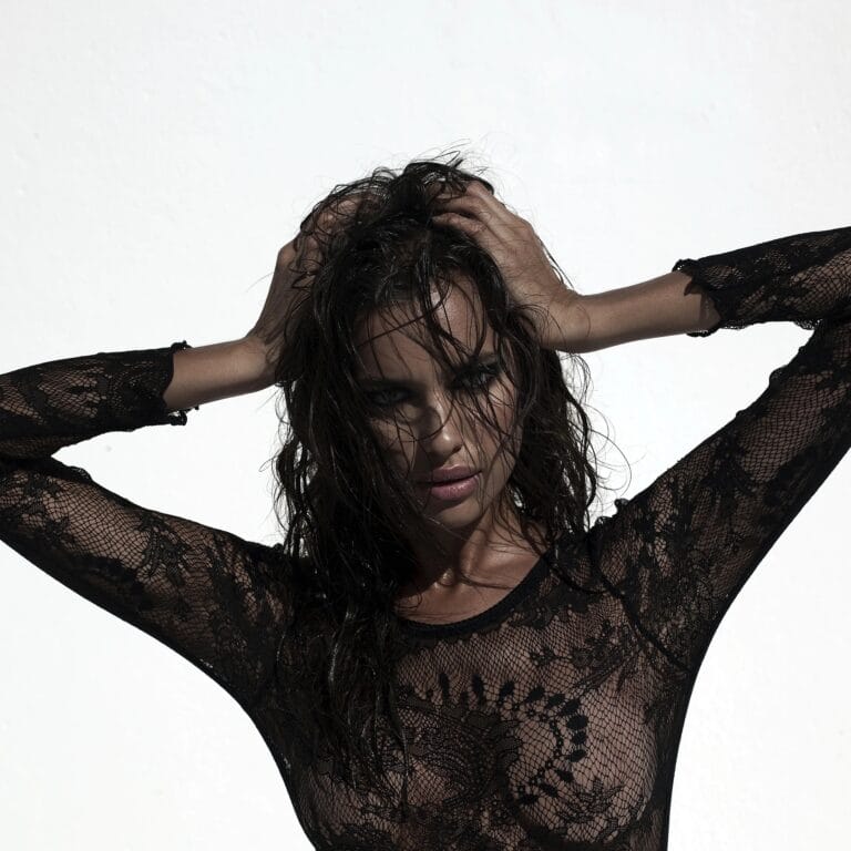 Irina Shayk: Wears a sheer black lace blouse that subtly reveals skin, with long…