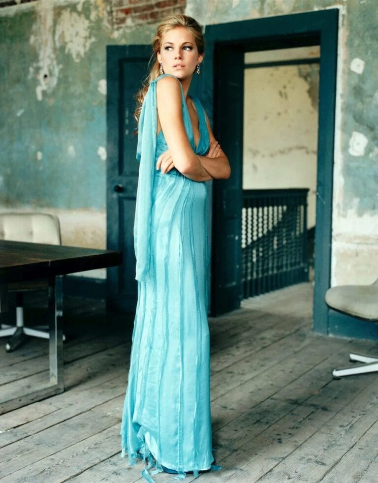 Sienna Miller: Wears a long dress in a soft blue tone, with a deep neckline and…