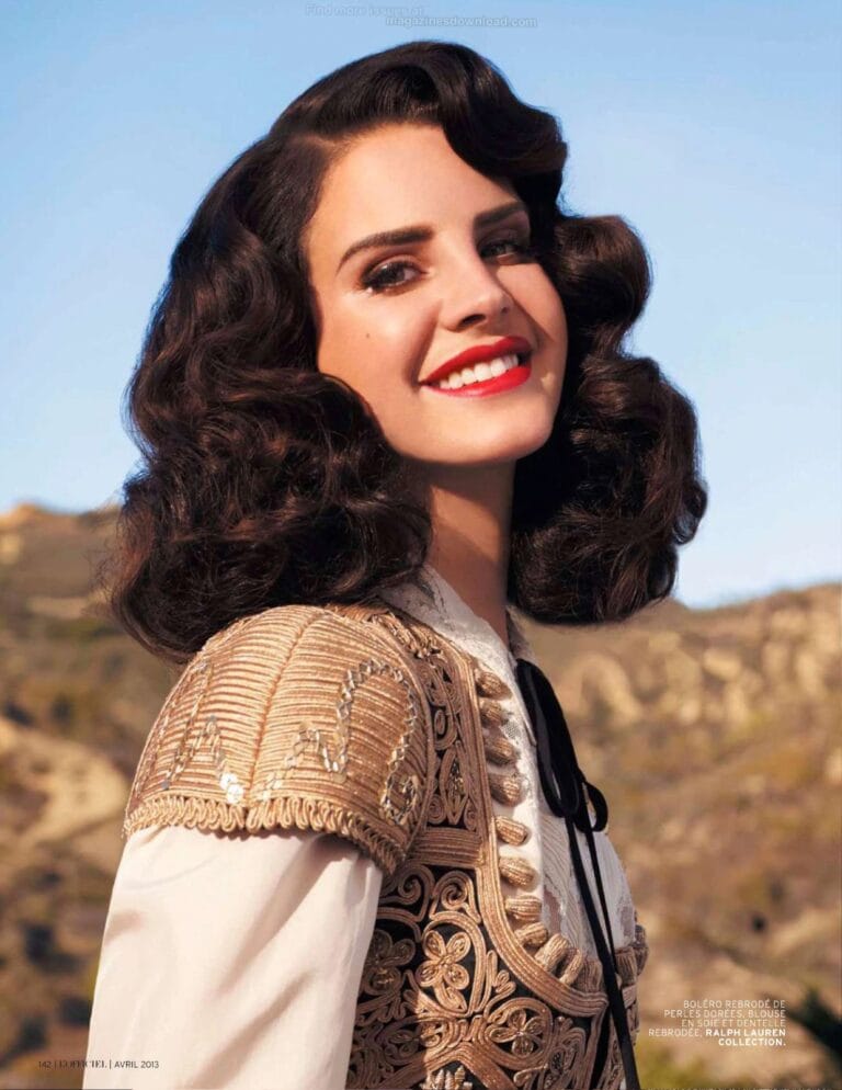 Lana Del Rey: Luce un bolero bordado en tonos dorados sobre una blusa blanca, con un elegante…
