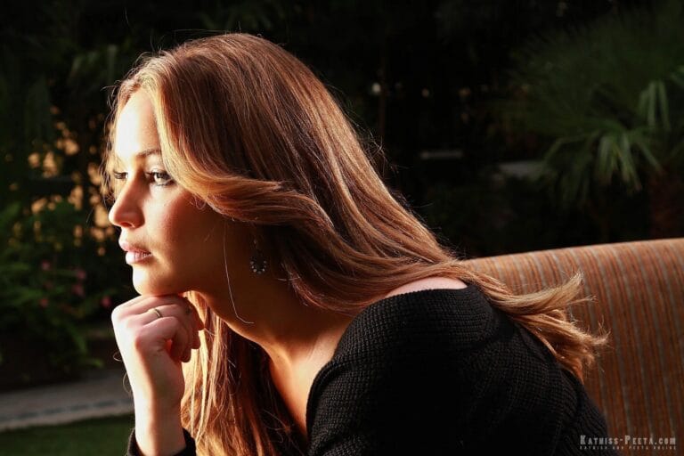 Jennifer Lawrence: Wears an oversized black sweater, leaning on a sofa with a posture…