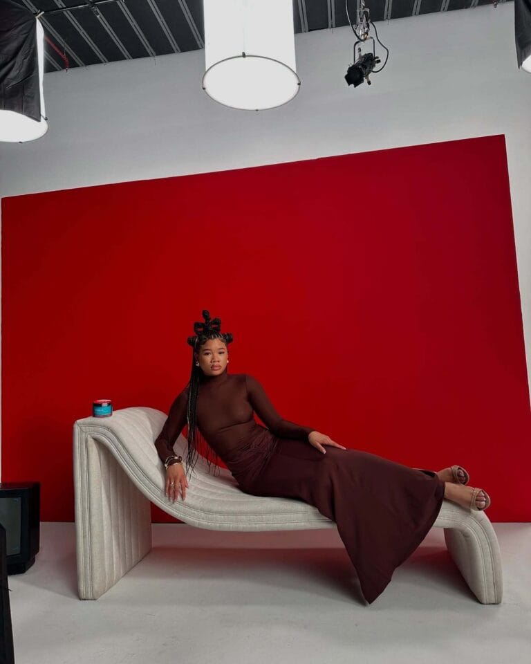 Storm Reid: Poses on a contemporary designer chair, in a fitted brown dress with long…