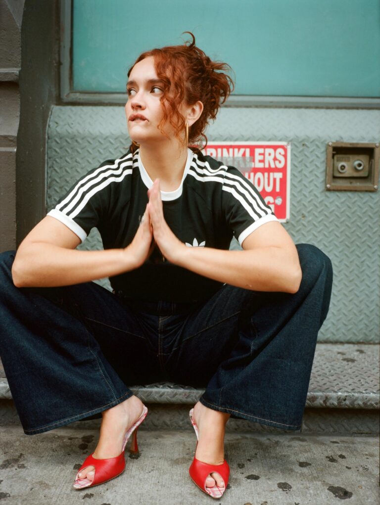 Olivia Cooke: Crouching on a staircase, wearing a black T-shirt with white stripes…
