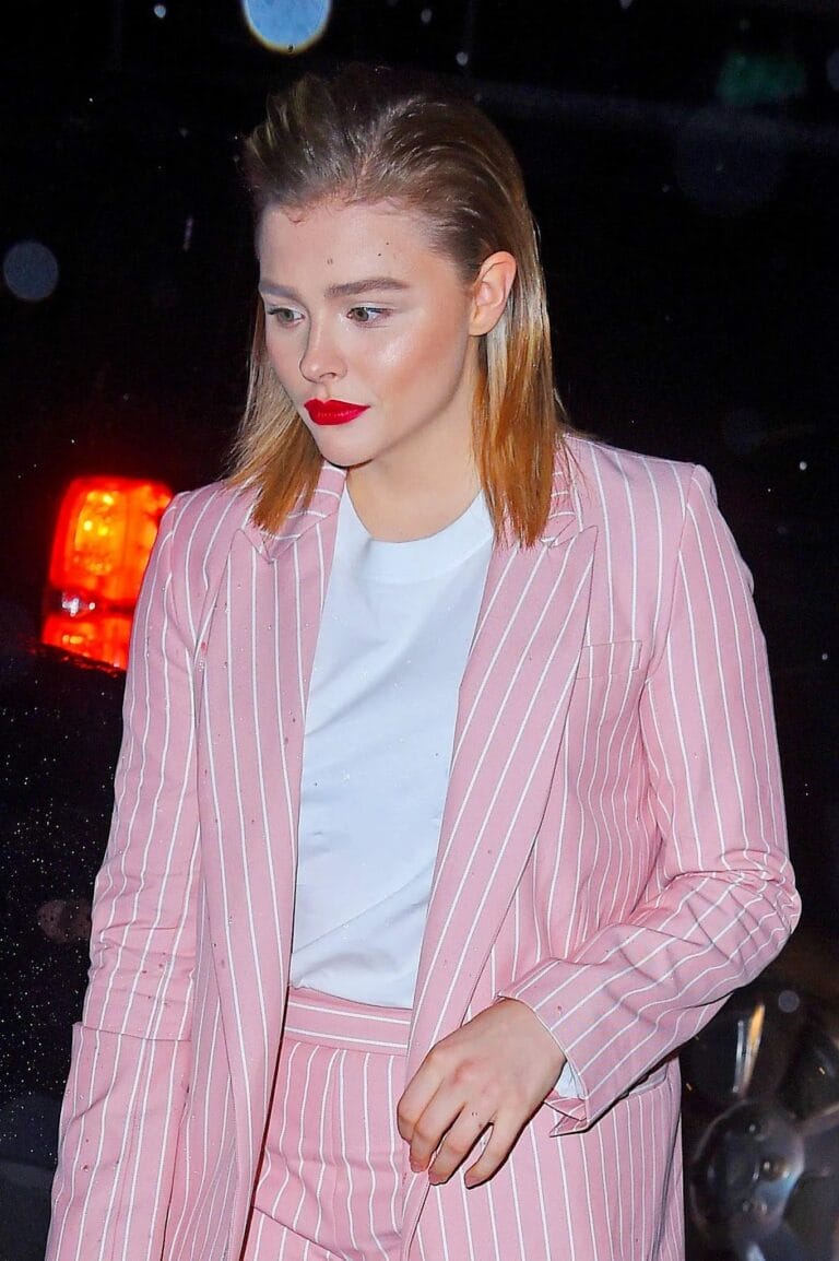 Chloë Grace Moretz: Wears a light pink two-piece suit with white stripes, pairing…