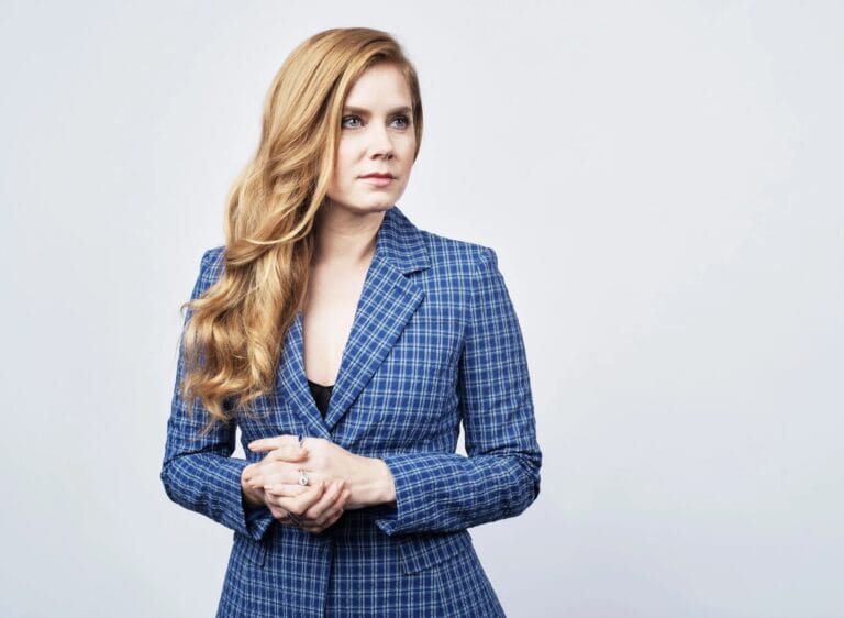 Amy Adams: Wears a blue plaid blazer over a black blouse, with a sophisticated air…