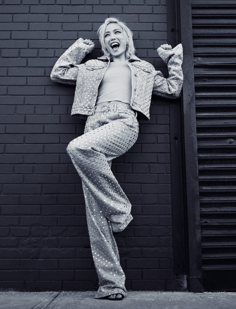 Pom Klementieff: Posa con energía, apoyada en una pared de ladrillo, luciendo un conjunto de chaqueta…