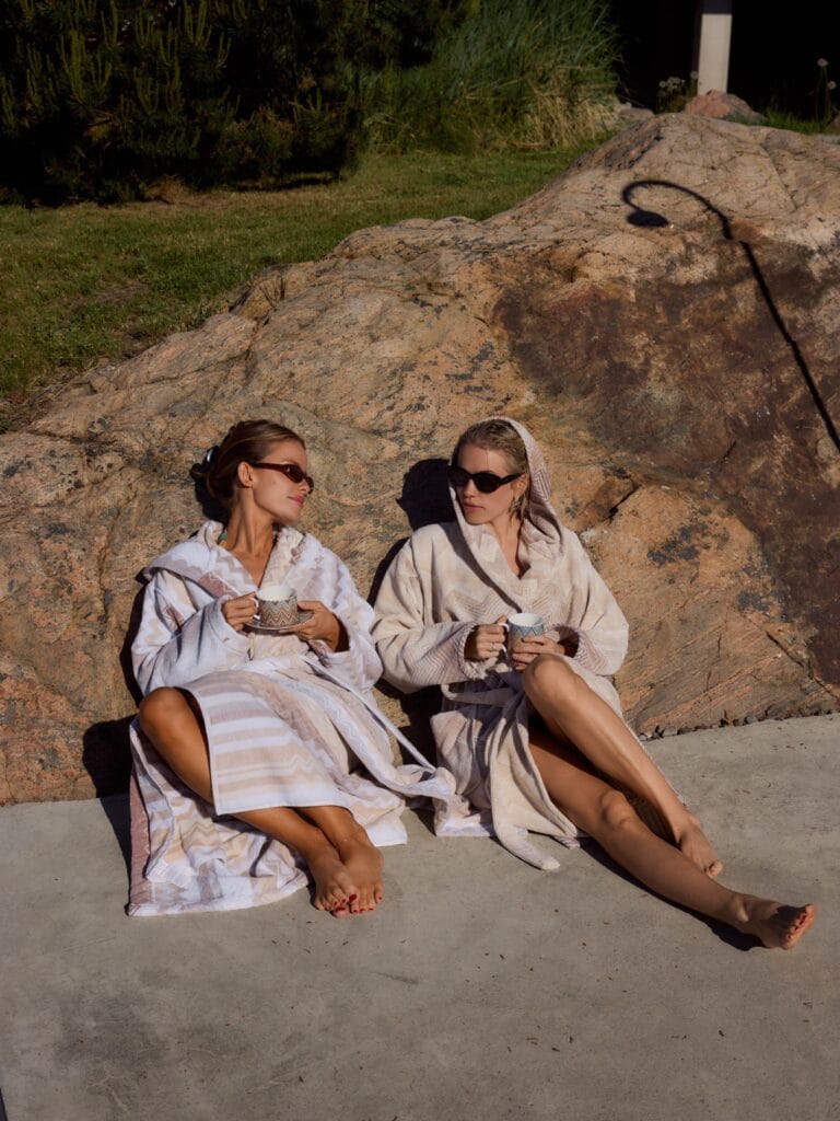 Thea Sofie Loch Næss: They pose relaxed on a rock, wearing light bathrobes, one with details in…