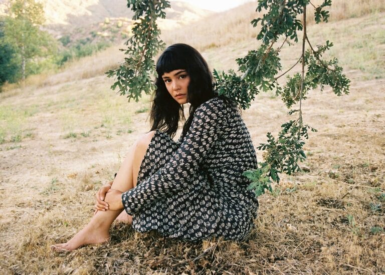 Courtney Eaton: Posa sobre la hierba, descalza, con un vestido largo de estampado floral en tonos…