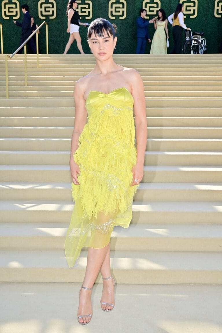 Courtney Eaton: Luce un vestido amarillo vibrante con detalles de flecos y un corte asimétrico, destacando…