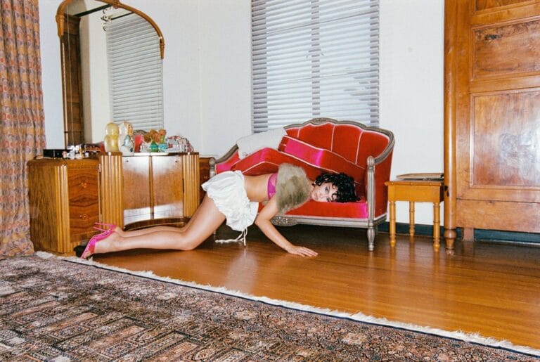 Courtney Eaton: Posa en una habitación vintage, con un look audaz que combina un sujetador rosa…
