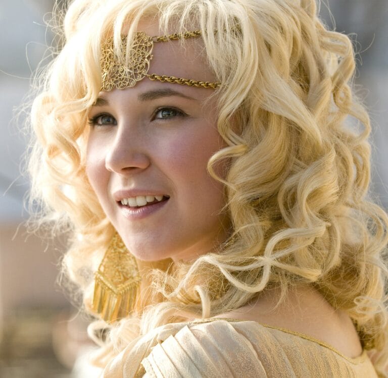 Juno Temple: Luce un vestido dorado con detalles suaves y un elegante tocado dorado que enmarca…
