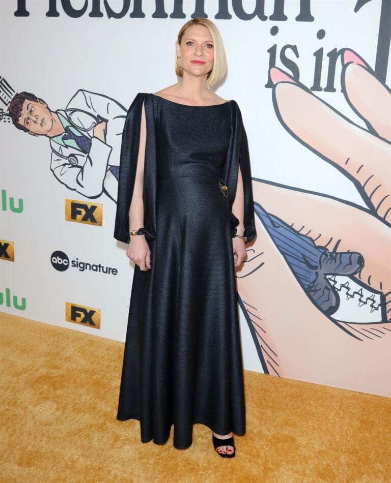Claire Danes: Wears a long, elegant black dress with wide sleeves that fall…