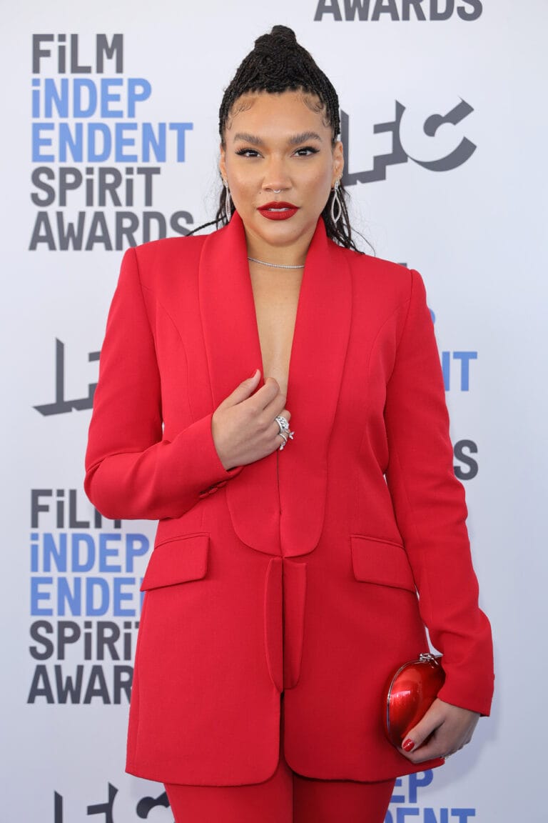 Emmy Raver-Lampman: Wears a bold red suit with a modern cut, featuring a subtle V-neckline…