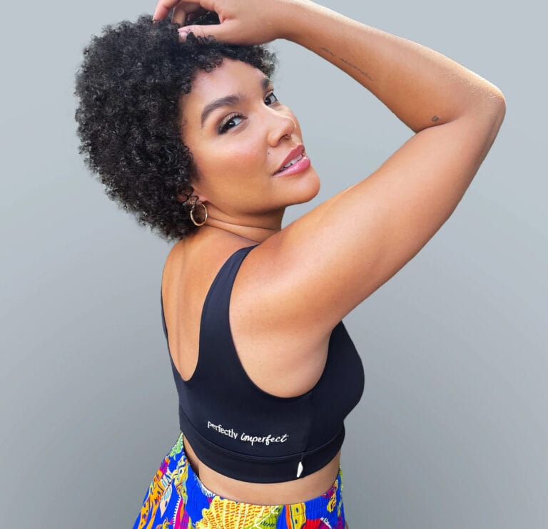 Emmy Raver-Lampman: Wears a black sleeveless top with the phrase "perfectly imperfect" on one side,…