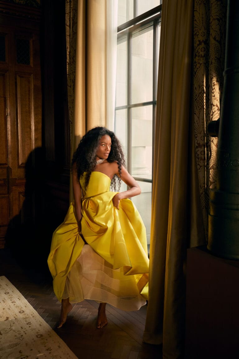 Naomie Harris: She wears a sleeveless yellow dress, voluminous and elegant, that flows gracefully…