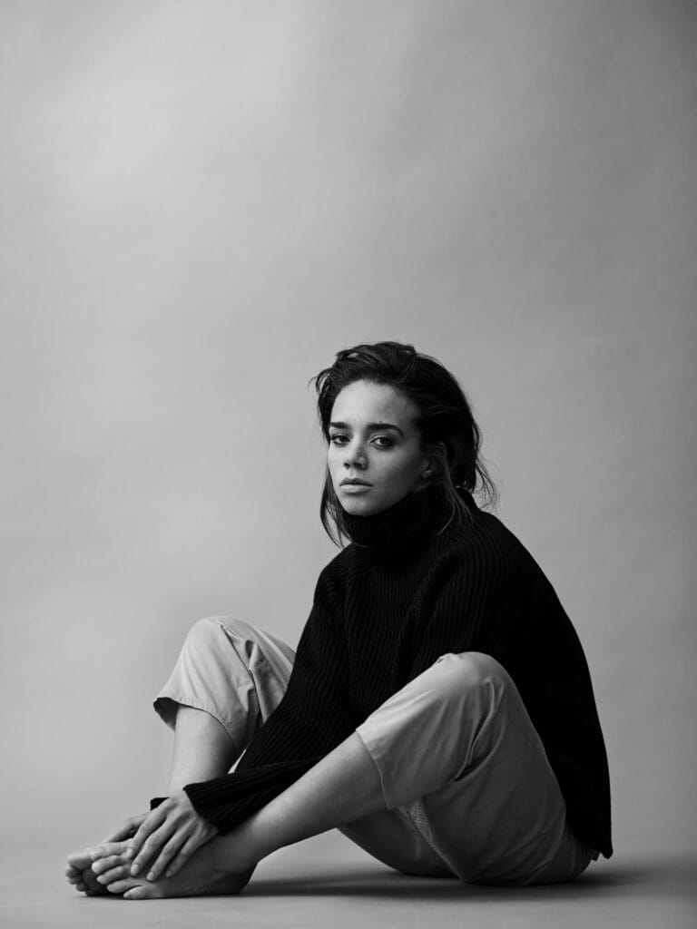 Hannah John-Kamen: Luce un suéter negro de cuello alto, con un estilo relajado, mientras está sentada…
