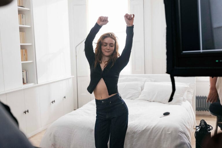 Sadie Sink: Wears a fitted black top that shows off part of her midriff, paired with…