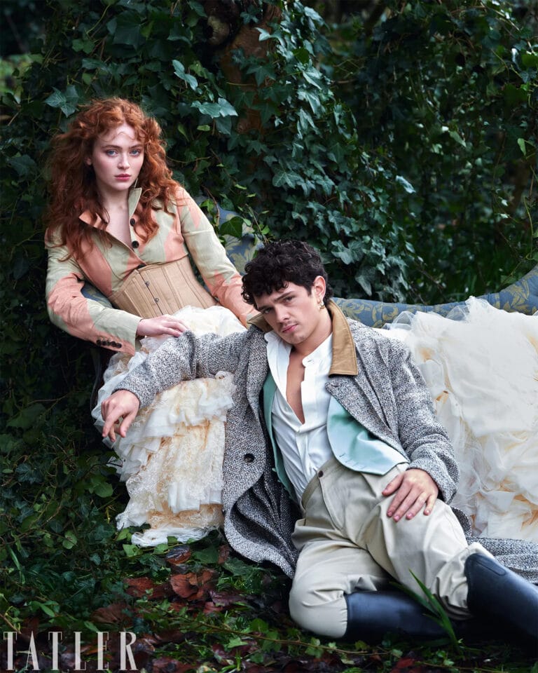 Sadie Sink: Wears a soft-toned corset and a long-sleeve blouse, with hair…