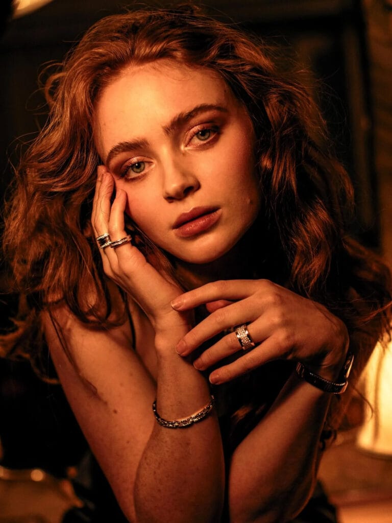 Sadie Sink: Wears a simple blouse while posing with one hand on her head and the…