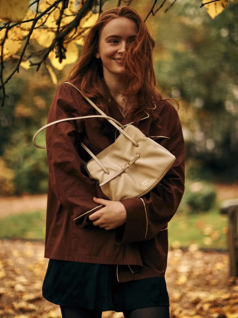 Sadie Sink: Wearing an oversized shirt in brown tones with gold details, paired…