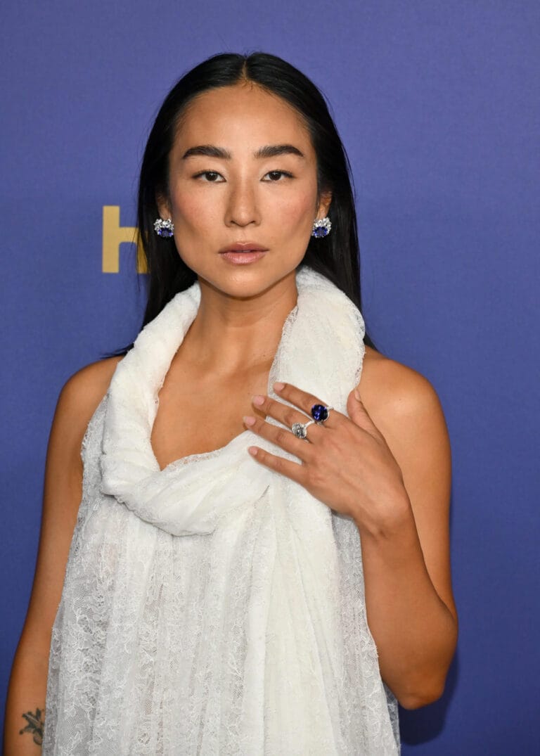 Greta Lee: Wears a white lace top that falls softly over the shoulders, creating a…