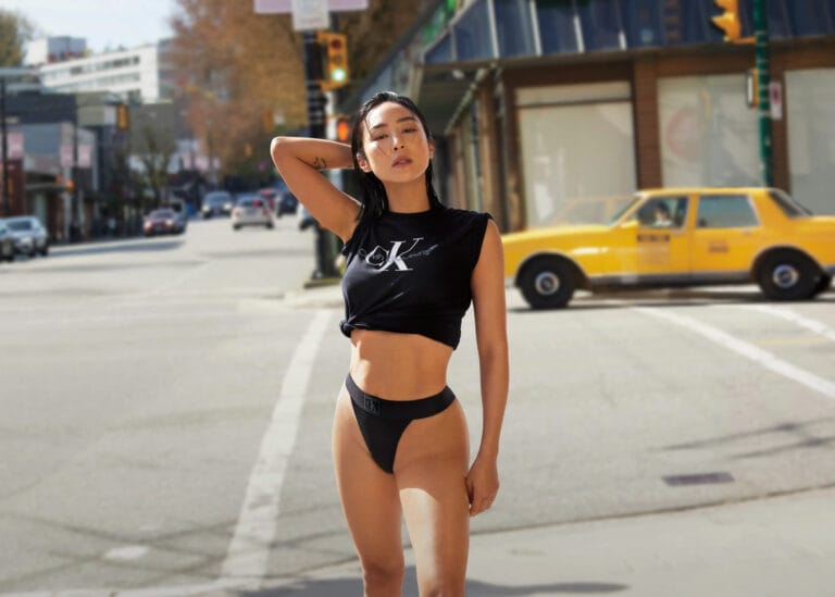 Greta Lee: Wears a fitted black top with a logo and high-cut black briefs,…