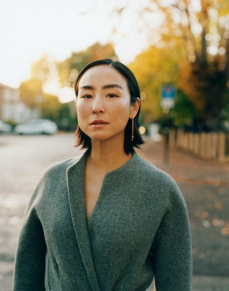 Greta Lee: Wears a gray wool coat with an elegant cut and a neckline in…