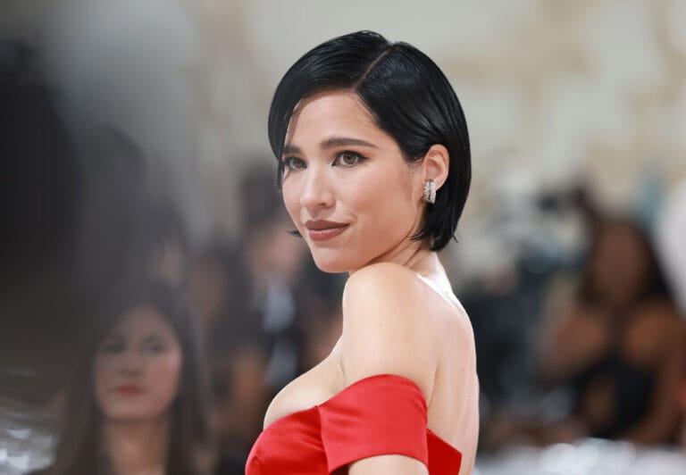 Kelsey Asbille: Wears a striking red dress with an asymmetrical neckline that elegantly highlights her figure.…