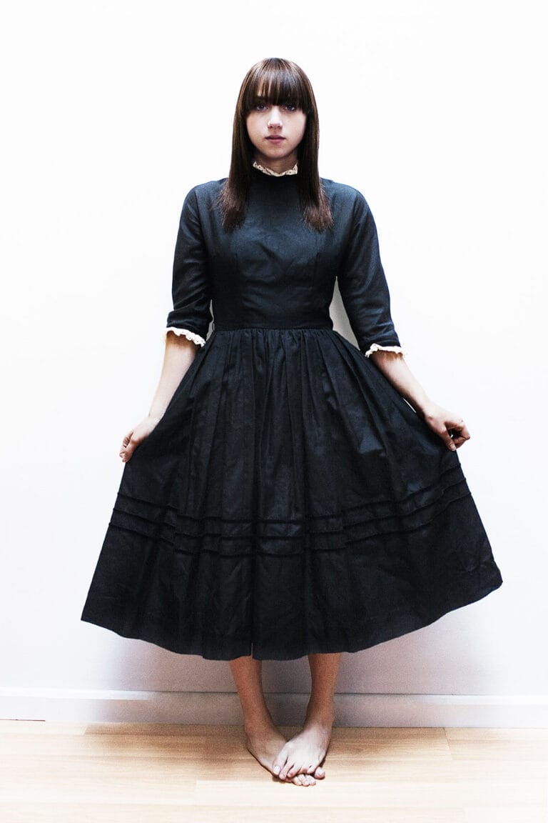 Zoe Kazan: Wears a black midi dress with three-quarter sleeves, adorned with details…