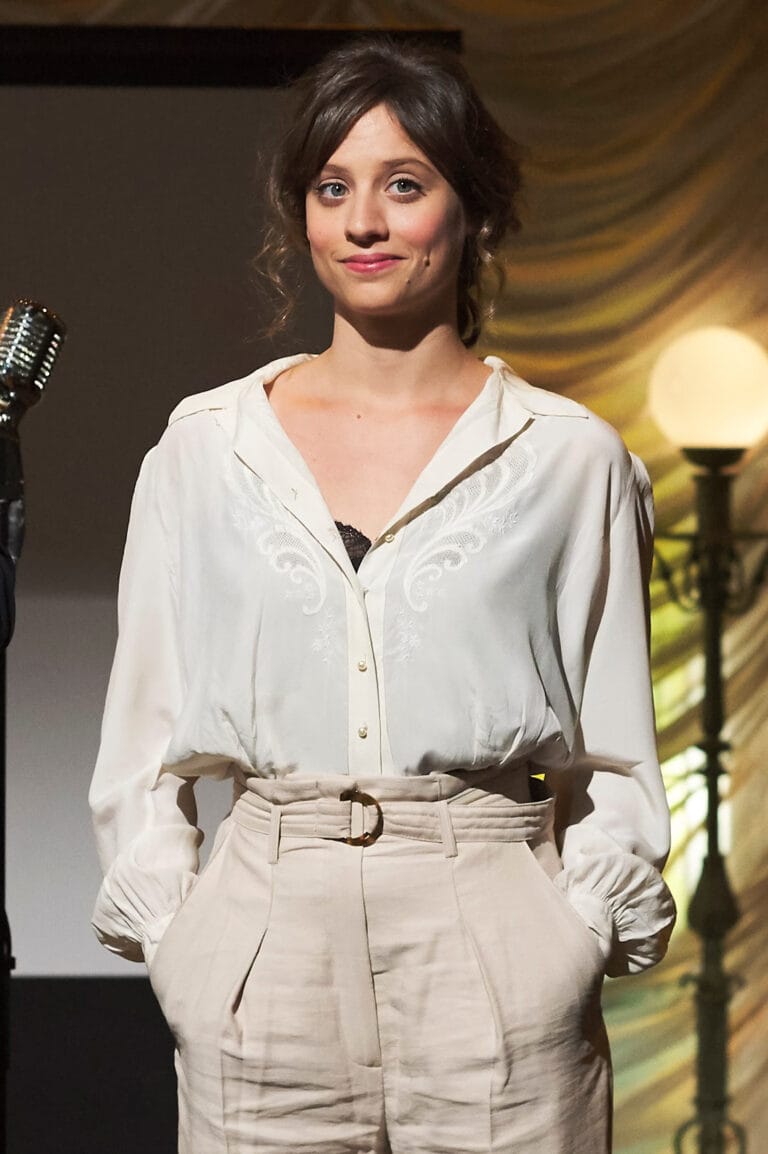 Michelle Jenner: Luce una blusa blanca con detalles bordados, ligeramente holgada, que deja entrever un delicado…