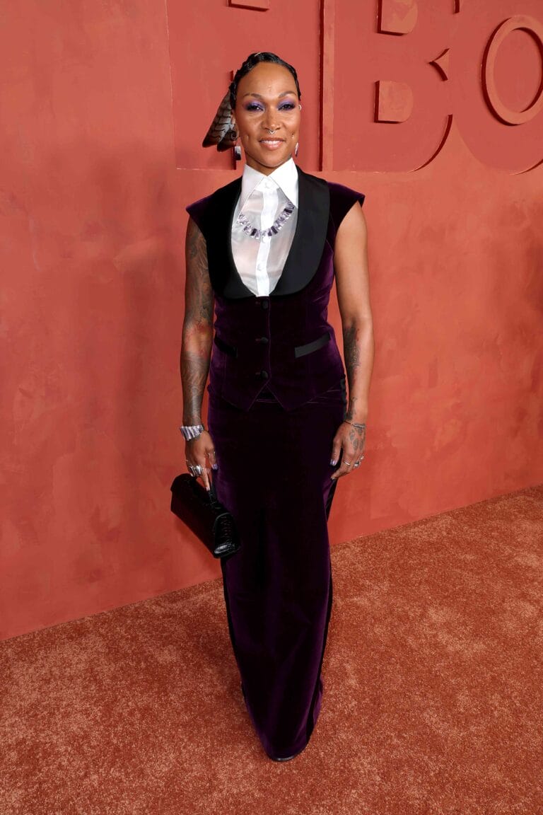 Kali Reis: Wears a long purple velvet dress with a black lapel detail that…
