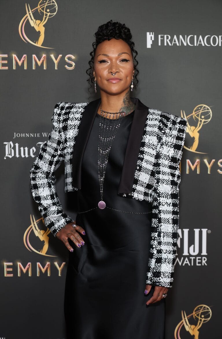Kali Reis: Wearing a black satin dress with a eye-catching white-and-…