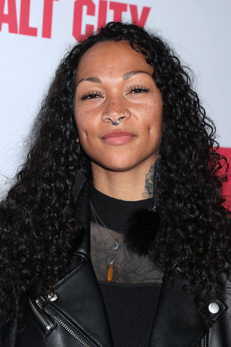 Kali Reis: Wears a black leather jacket over a sheer blouse, showcasing a bold style…