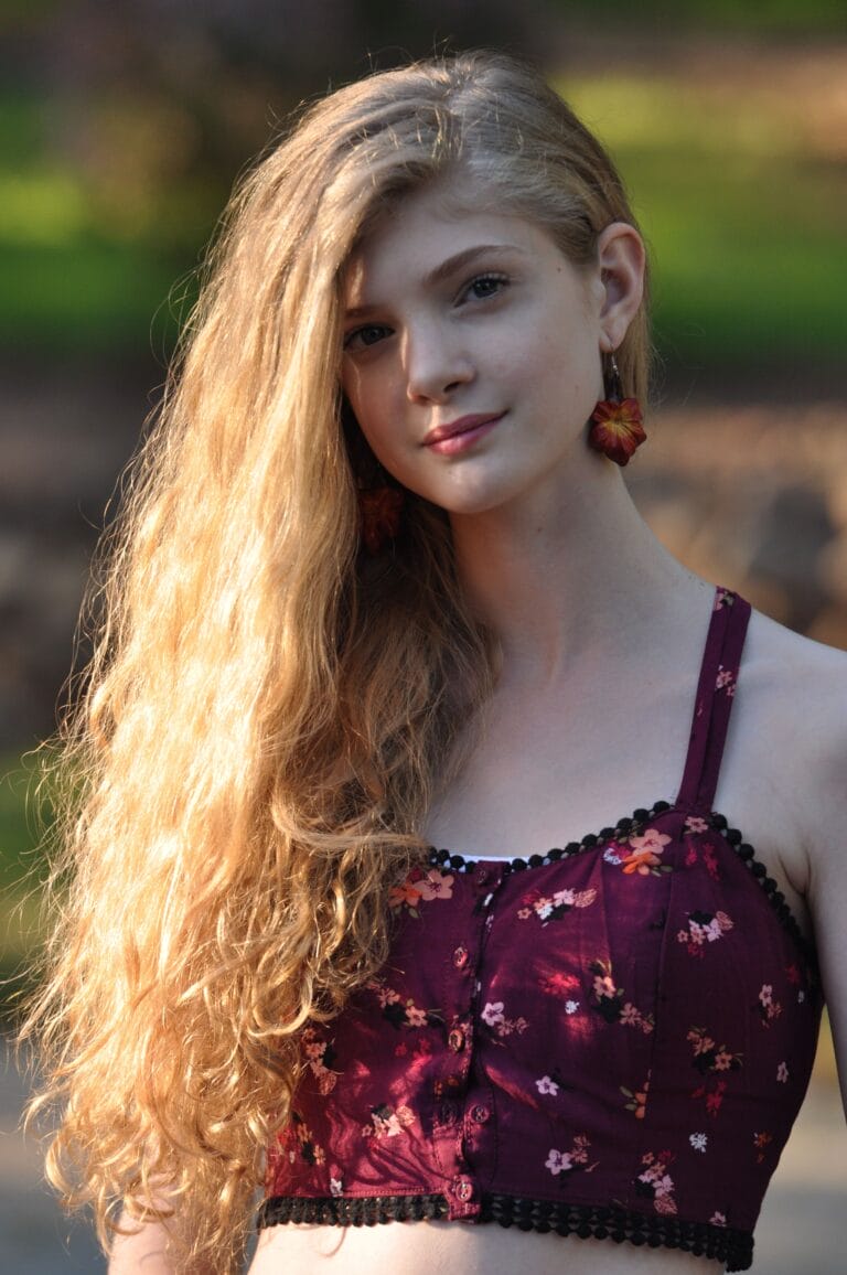 Elena Kampouris: Wearing a short floral top in burgundy tones, with black details and…