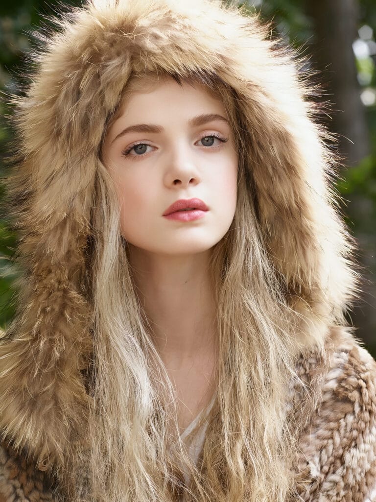 Elena Kampouris: Wearing a fur-trimmed hooded coat that frames her face with…