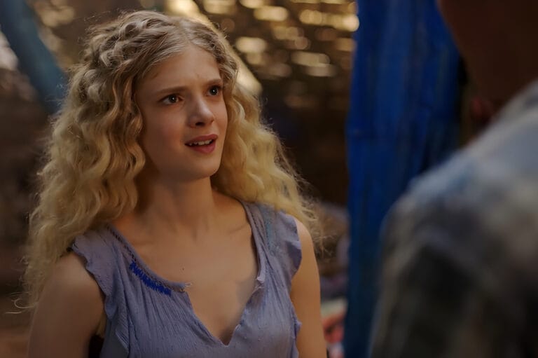 Elena Kampouris: Wearing a lavender blouse with textured details and one strap slipping down,…