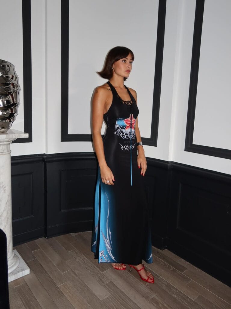 Ella Purnell: Wears a long black dress with graphic blue and red details, highlighting her…