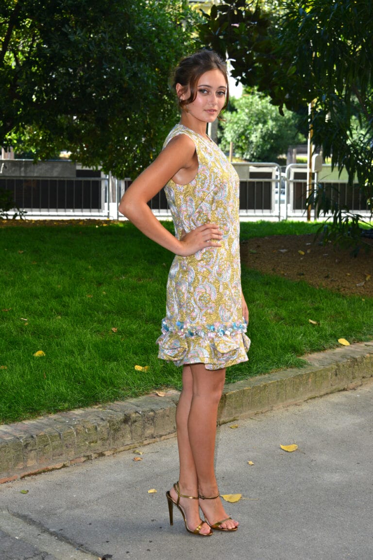 Ella Purnell: Wears a sleeveless floral-print dress in yellow and lilac tones, with…