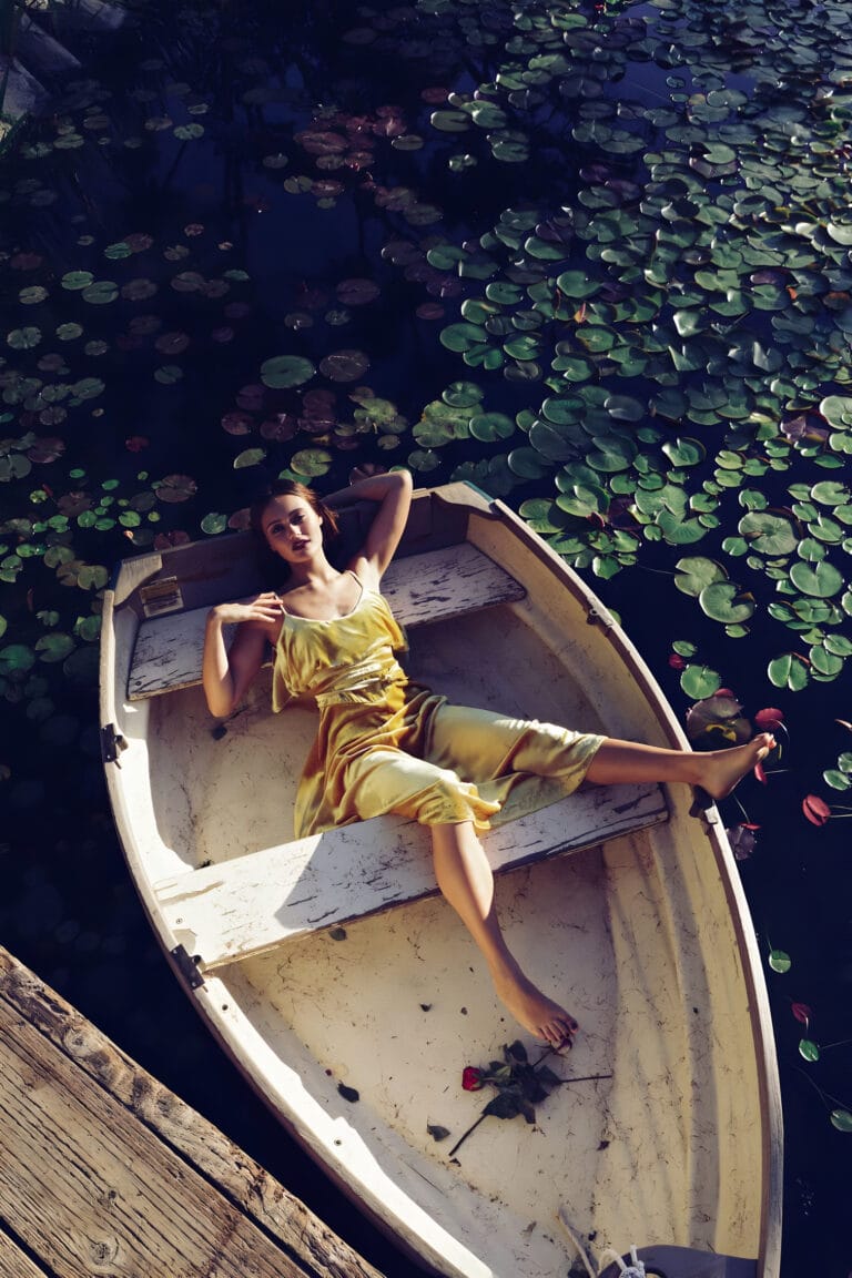 Ella Purnell: Wears a soft, flowing yellow silk dress while reclining on a…
