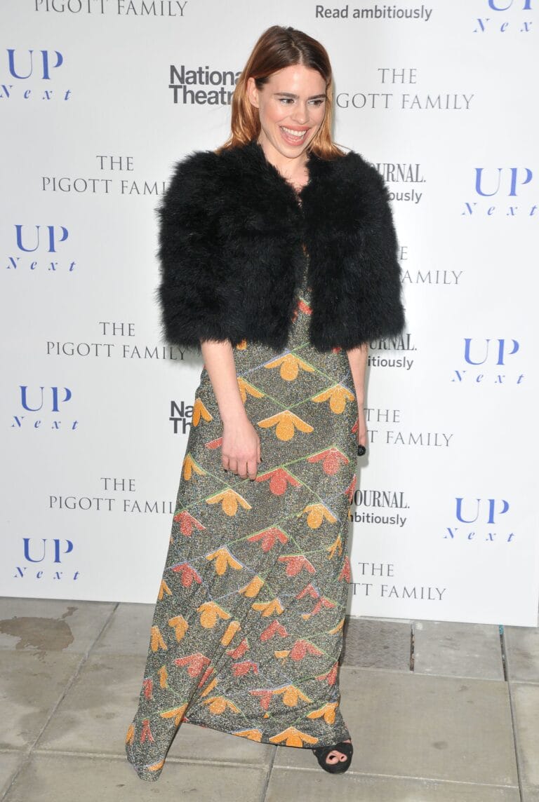 Billie Piper: Wears a long dress with a vibrant floral print in orange and green tones,…