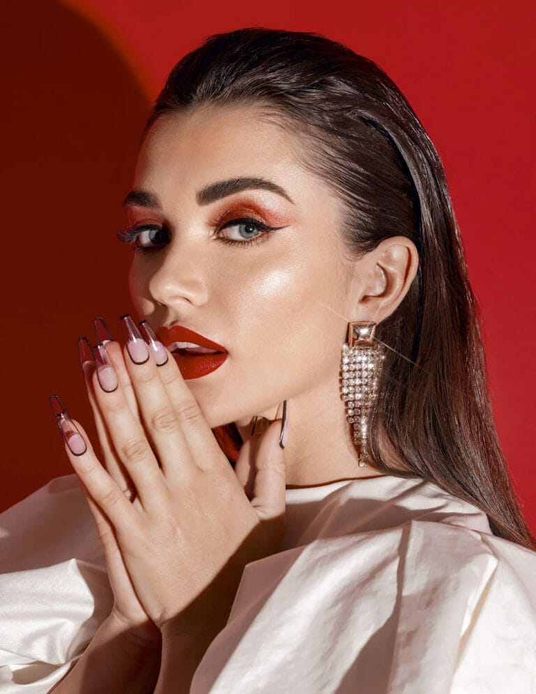 Amy Jackson: Wears a white blouse with voluminous sleeves, creating a bold contrast with the background…