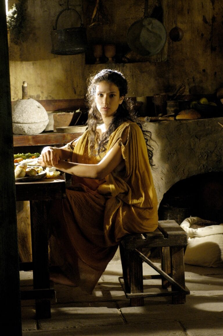 Indira Varma: Luce un vestido largo de tono mostaza, con un corte sencillo y sin mangas,…