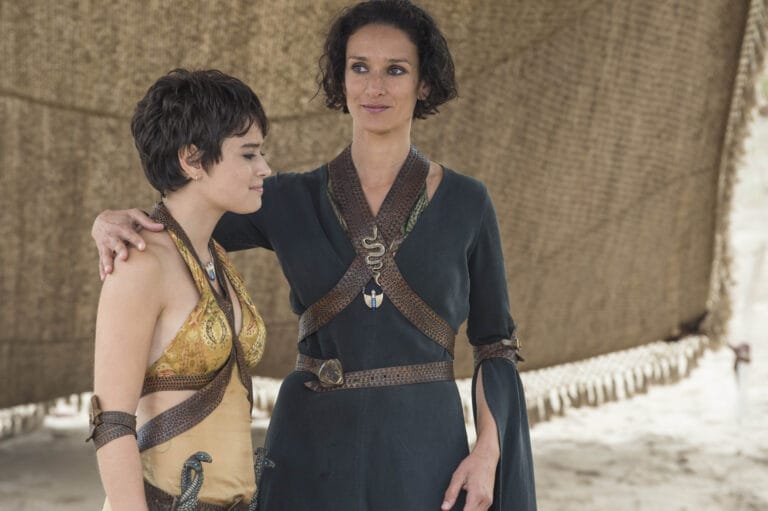 Indira Varma: Wears a black dress with a flowing cut and leather details that accentuate her…