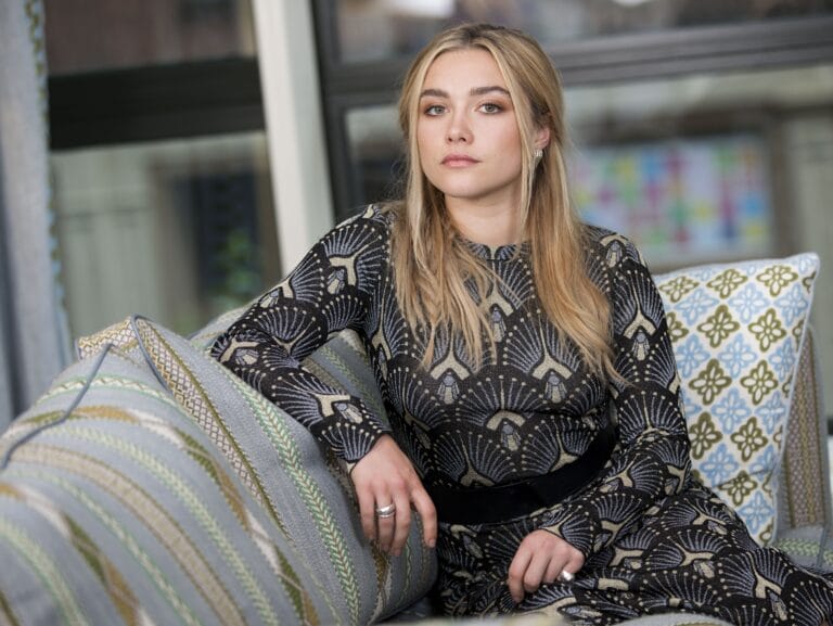 Florence Pugh: Luce un vestido negro de manga larga con un elegante estampado dorado, sentada sobre…