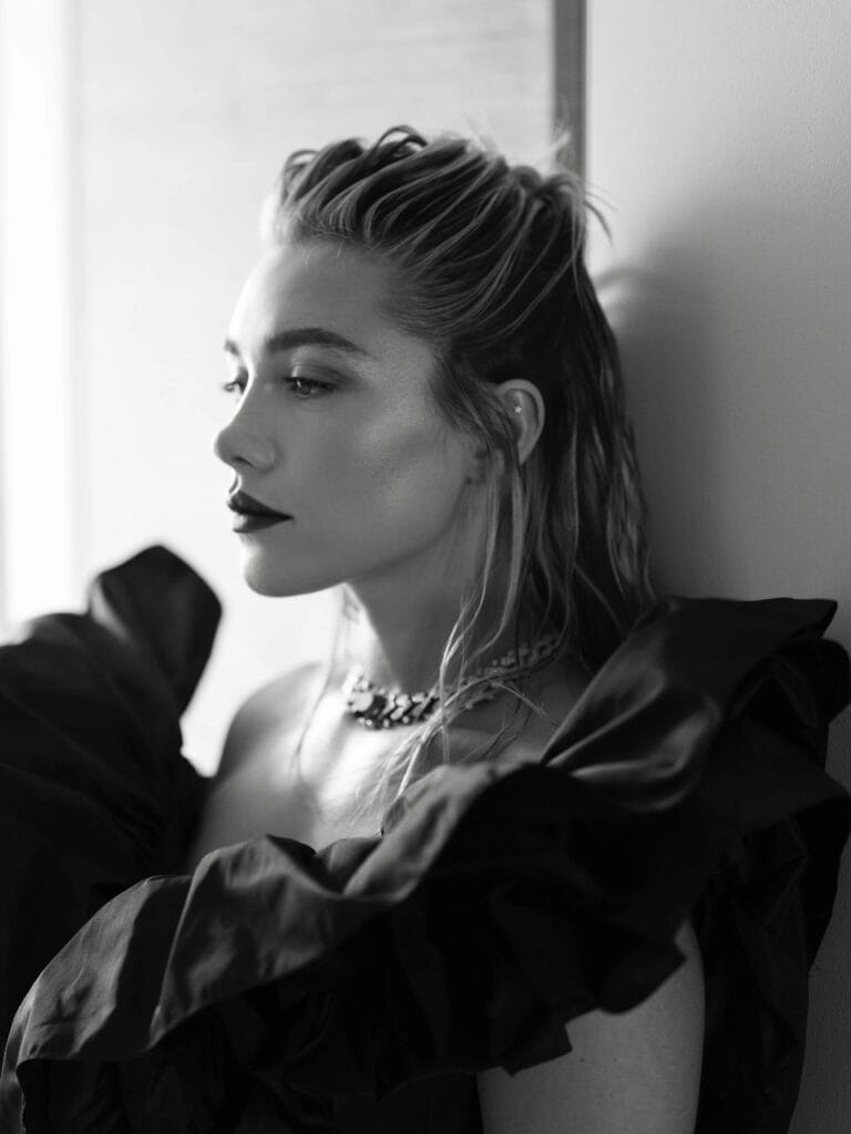 Florence Pugh: Luce un vestido negro con voluminosas mangas rizadas, apoyada contra la pared en un…
